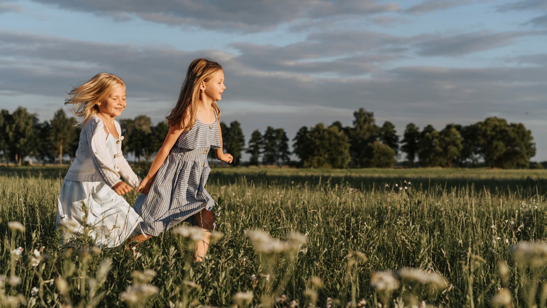 Two girls running through a summer meadow